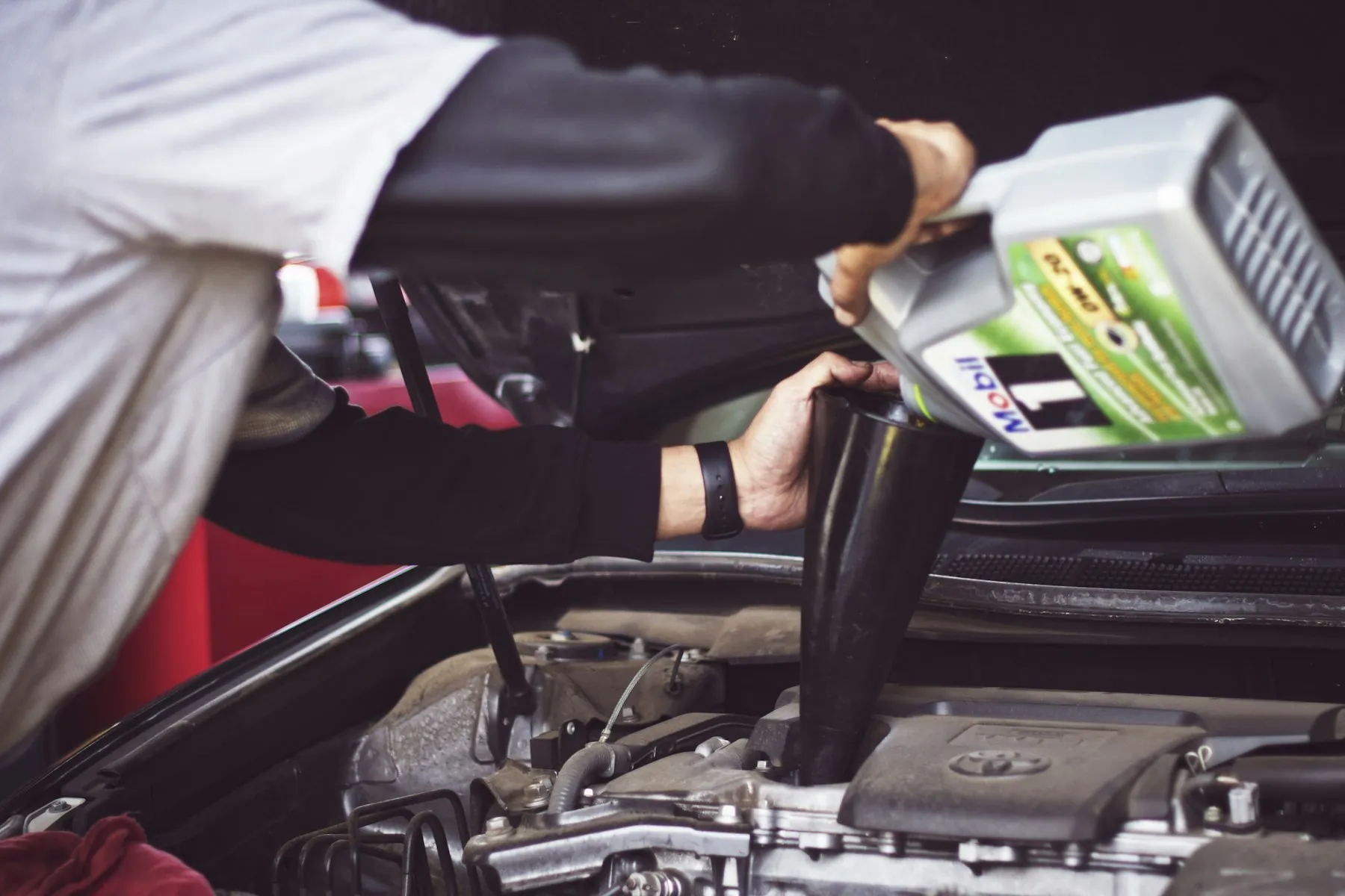 Mechanic pouring fresh engine oil during a mobile car service visit in Dubai