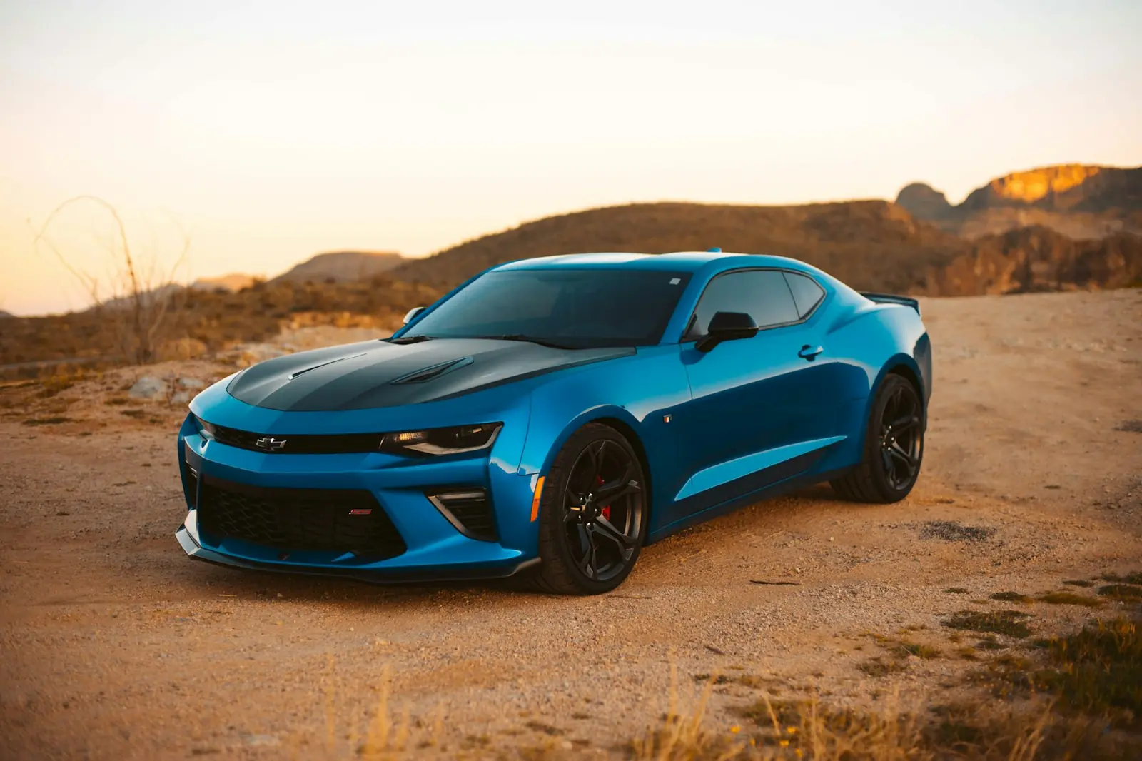 Sports car parked on desert terrain outside Dubai at sunset